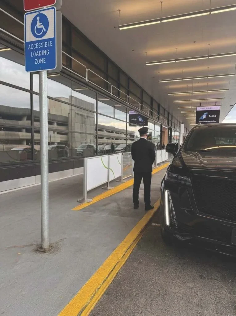 Uniformed Black Diamond chauffeur waiting at the Sea-Tac curb beside a black SUV